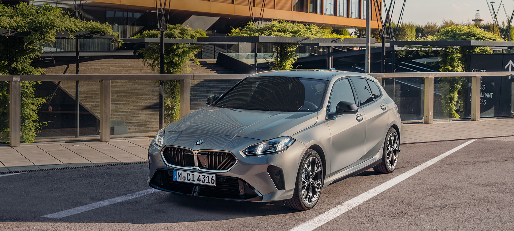 Grauer BMW 1er auf einem Parkplatz vor einem Gebäude.