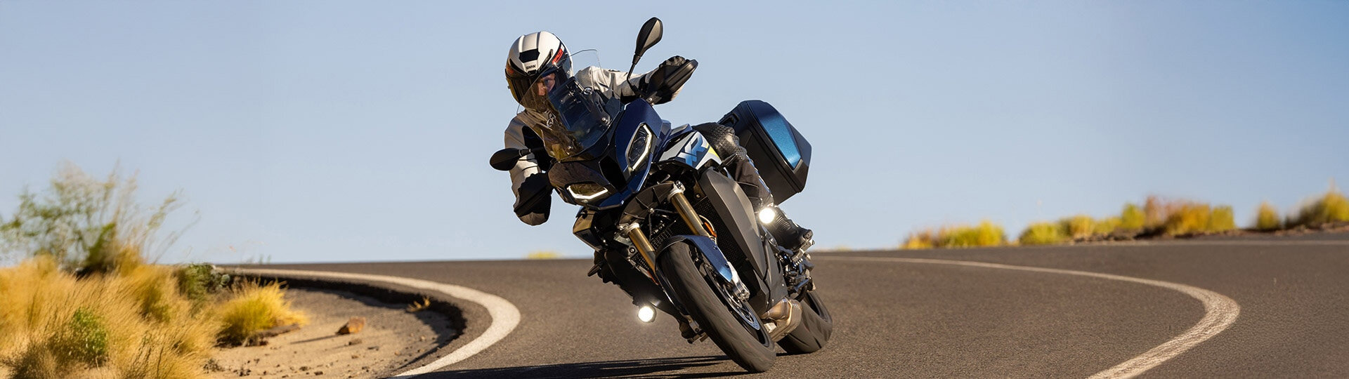 BMW Motorrad mit Nano Zusatzscheinwerfern – maximale Sicht bei jeder Kurve | Wahl-Group BMW Motorrad in Kurvenfahrt mit aktivierten Nano Zusatzscheinwerfern bei Tageslicht auf kurviger Landstraße