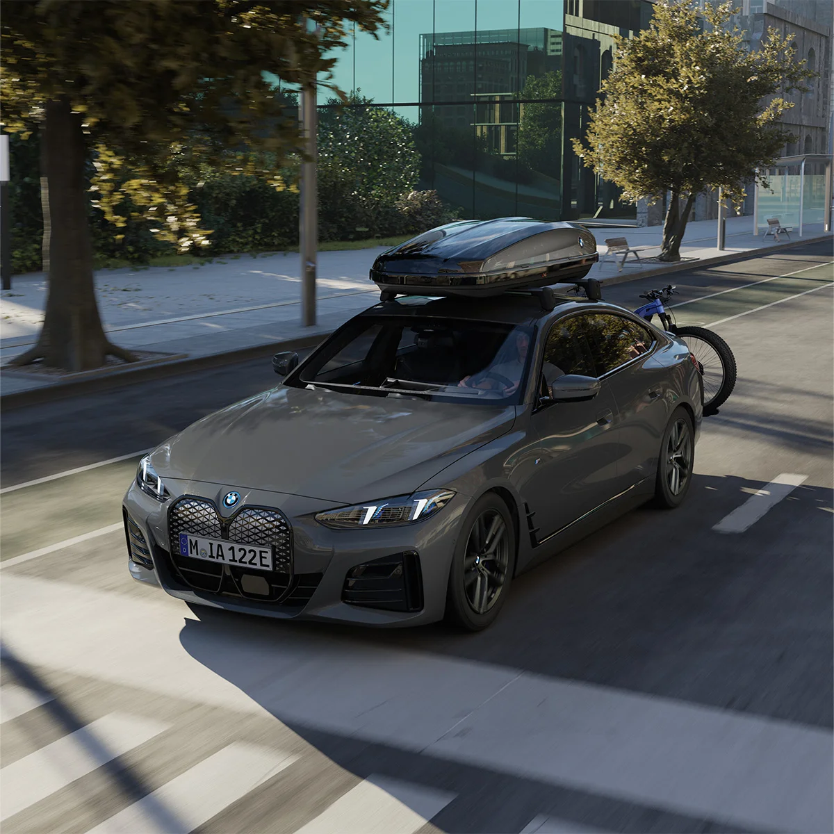 Grauer BMW mit montierter Dachbox und Fahrradträger fährt durch die Stadt – Zubehör bei der Wahl-Group