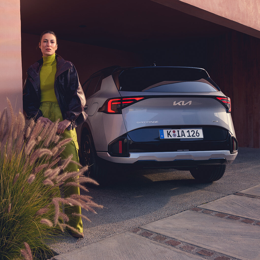 Kia Sportage HEV Heckansicht – eleganter Hybrid-SUV bei der Wahl-Group erleben Kia Sportage HEV Rückansicht mit stilvoller Person – modernes Hybrid-SUV bei der Wahl-Group