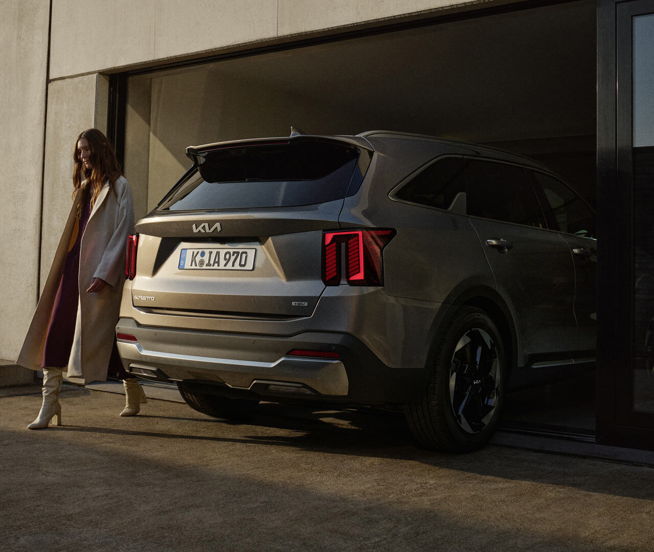 Kia Sorento – Intelligente Heckklappe für komfortables Beladen, ganz ohne Berührung Frau am Kia Sorento mit geöffneter intelligenter Heckklappe – freihändiger Zugang zum Kofferraum durch Smart-Key-Funktion