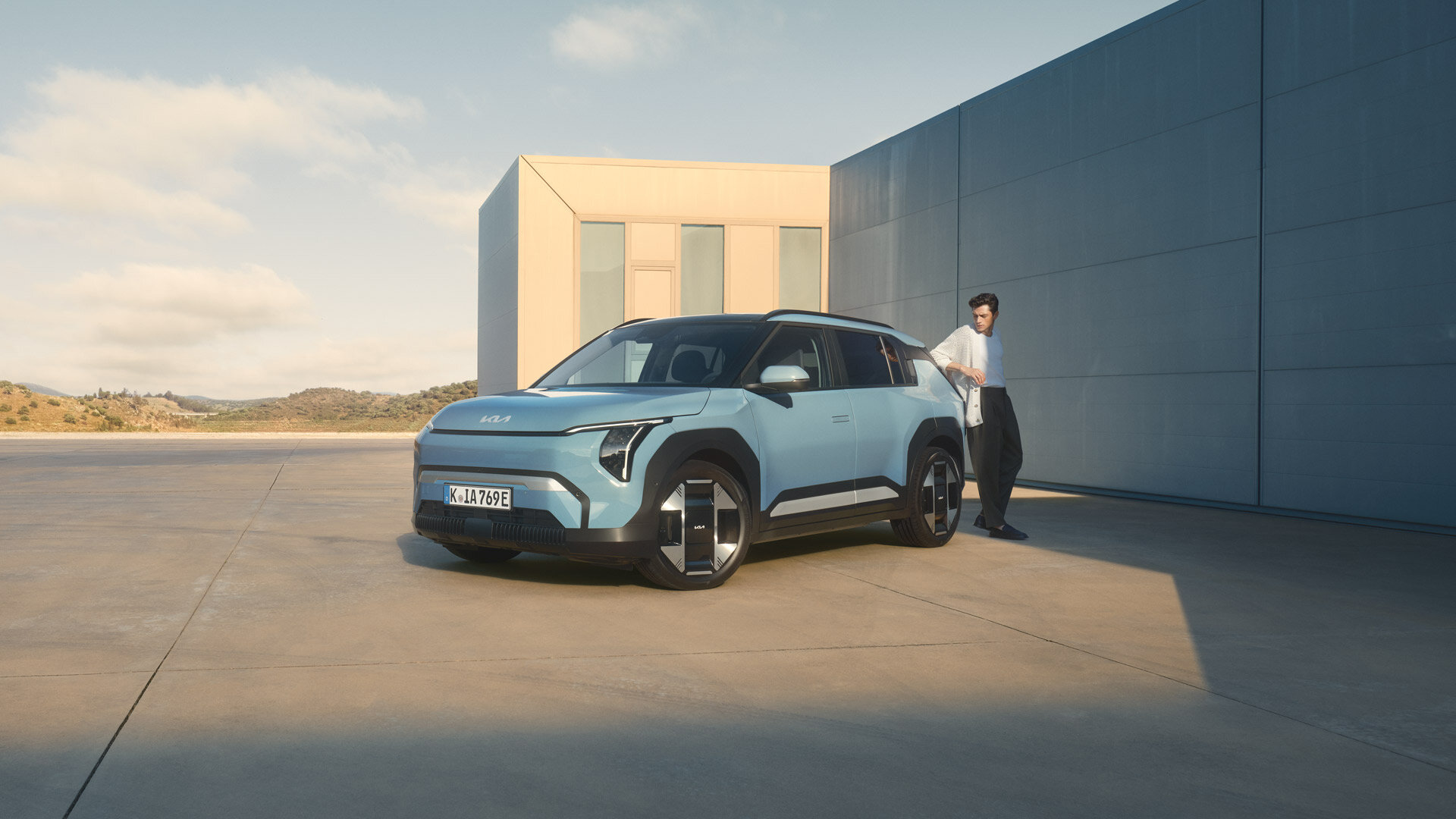Kia EV3 - Elektro-SUV mit 605 km Reichweite - Jetzt bei der Wahl-Group Kia EV3 in hellblau von der Seite vor moderner Architekturkulisse mit klaren Linien und aerodynamischem Design