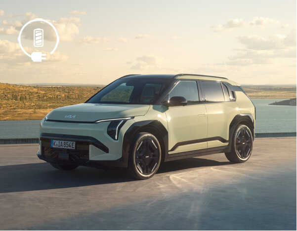 Kia EV3 Elektro-SUV in hellem Metallic auf einer Küstenstraße bei Sonnenuntergang