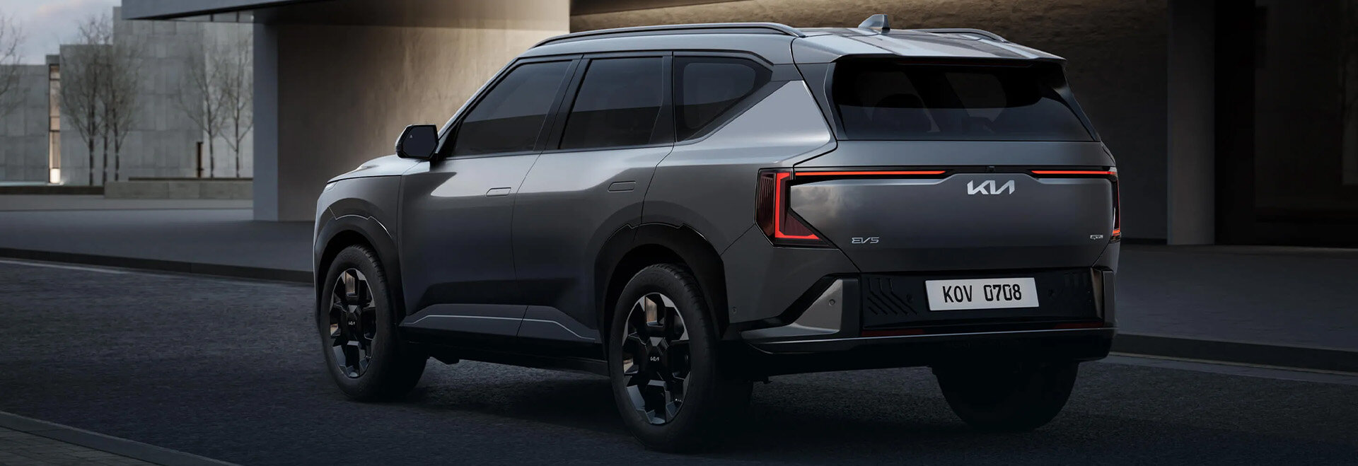 Dynamische schräg hintere Ansicht des Kia EV5 Elektro-SUV in Grau auf der Straße bei der Wahl-Group