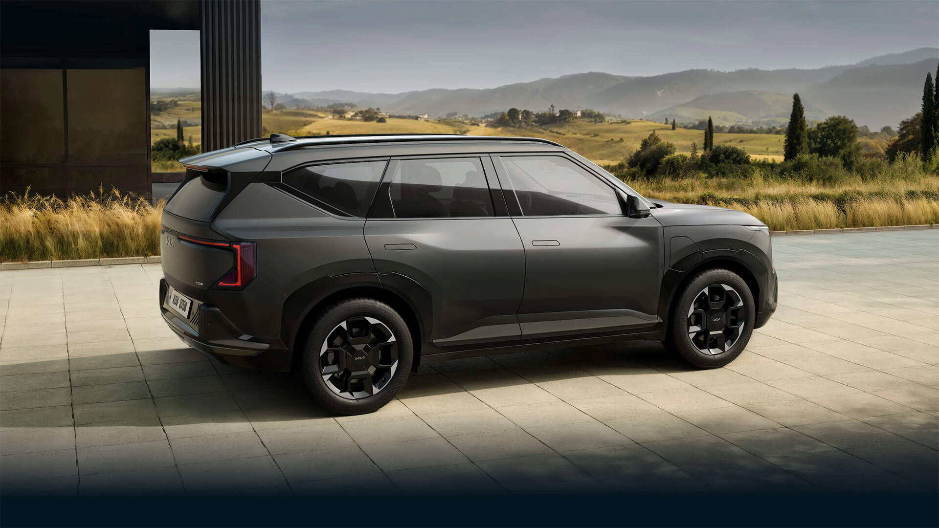 Kia EV5 Elektro-SUV in Grau schräg von hinten auf einer Terrasse mit Landschaft im Hintergrund bei der Wahl-Group