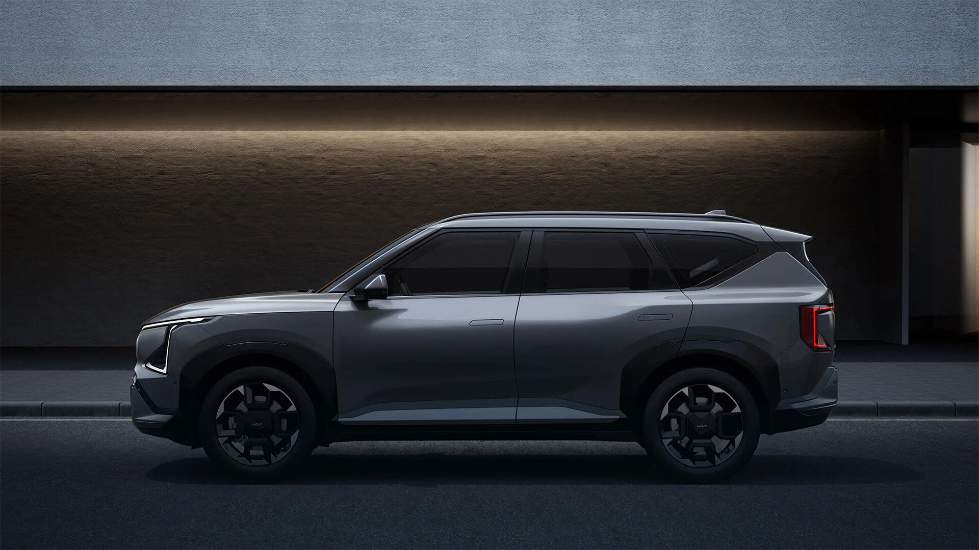 Seitenansicht des Kia EV5 Elektro-SUV in Grau auf der Straße vor einem Gebäude bei der Wahl-Group