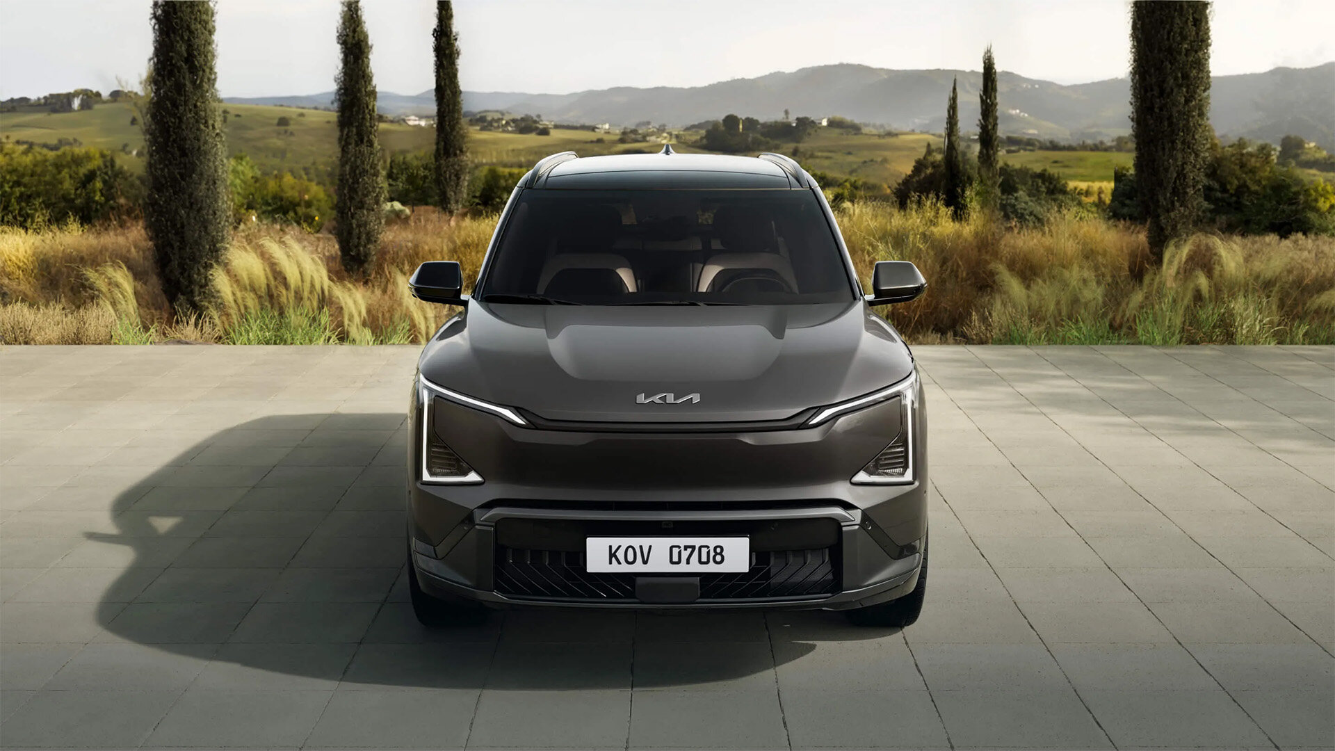 Frontansicht des Kia EV5 Elektro-SUV in Grau auf einer Terrasse mit Landschaft im Hintergrund bei der Wahl-Group