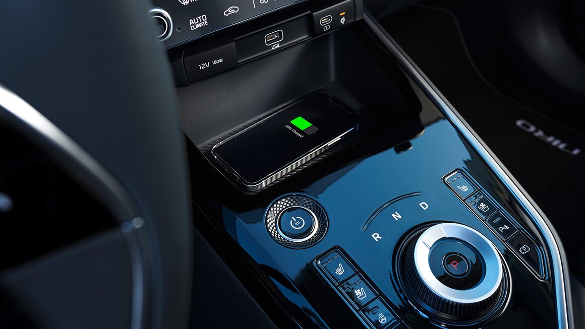 Kia Niro Schnellladefunktion – Komfortables Aufladen unterwegs Handy auf der Ladefläche des Kia Niro während der Schnellladefunktion in Benutzung