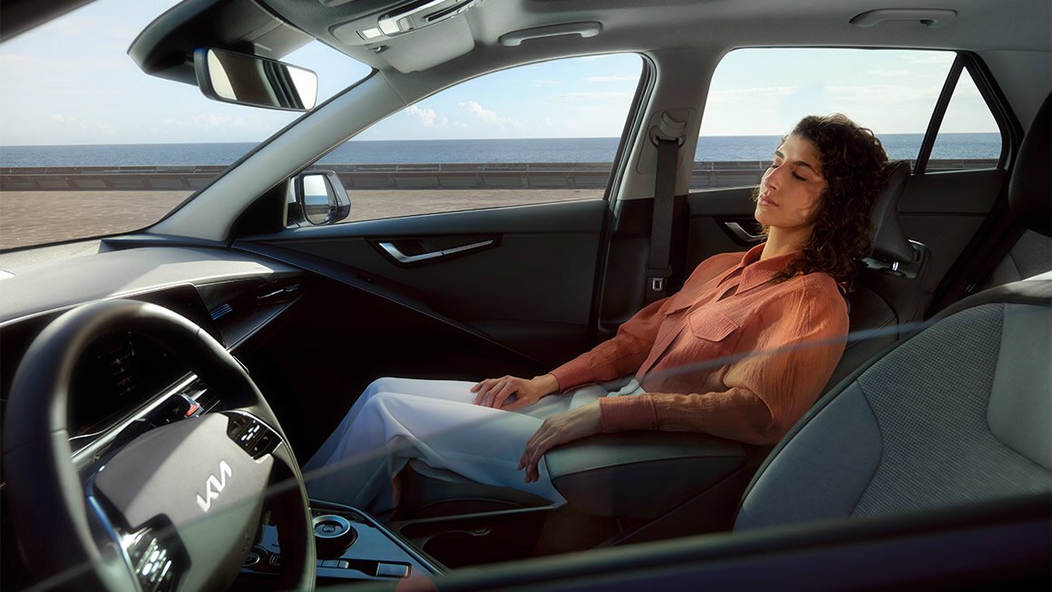 Kia Niro Relaxation – Entspannte Fahrt im komfortablen Beifahrersitz Frau entspannt im Beifahrersitz des Kia Niro, genießt den Komfort und die Ruhe der Fahrt