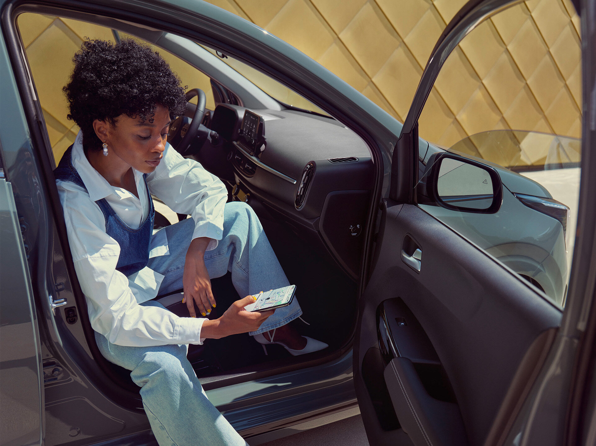 Entspannte junge Frau im Kia Picanto nutzt Smartphone-Connectivity, modernes Interieur mit hochwertiger Ausstattung und ergonomischen Sitzen