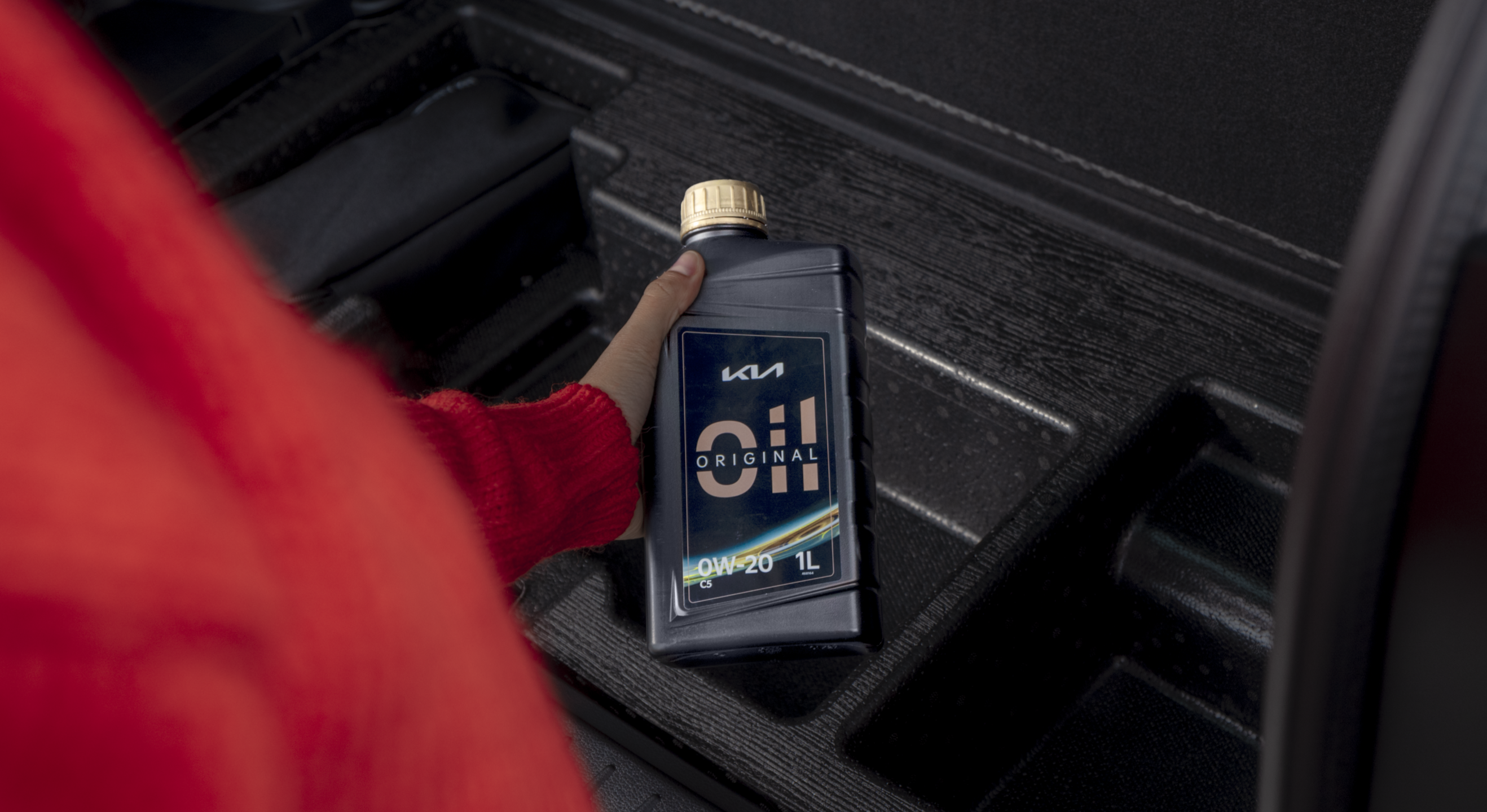 Ein Kia Kunde hält eine Flasche Kia Original Öl in der Hand.