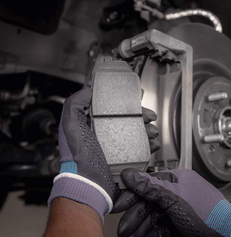 Ein Kia Techniker ersetzt Bremsbeläge und Bremsscheiben eines älteren Kia durch Kia Originalteile.