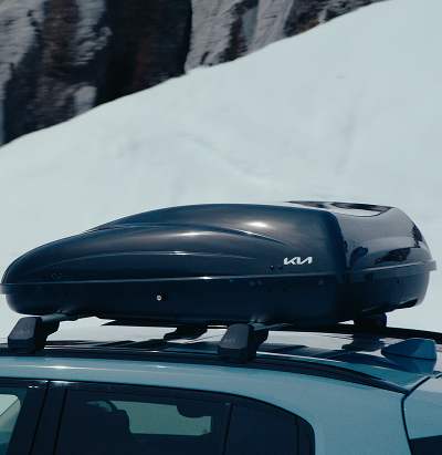 Kia Dachbox auf Querträgern vor einem verschneiten Hang