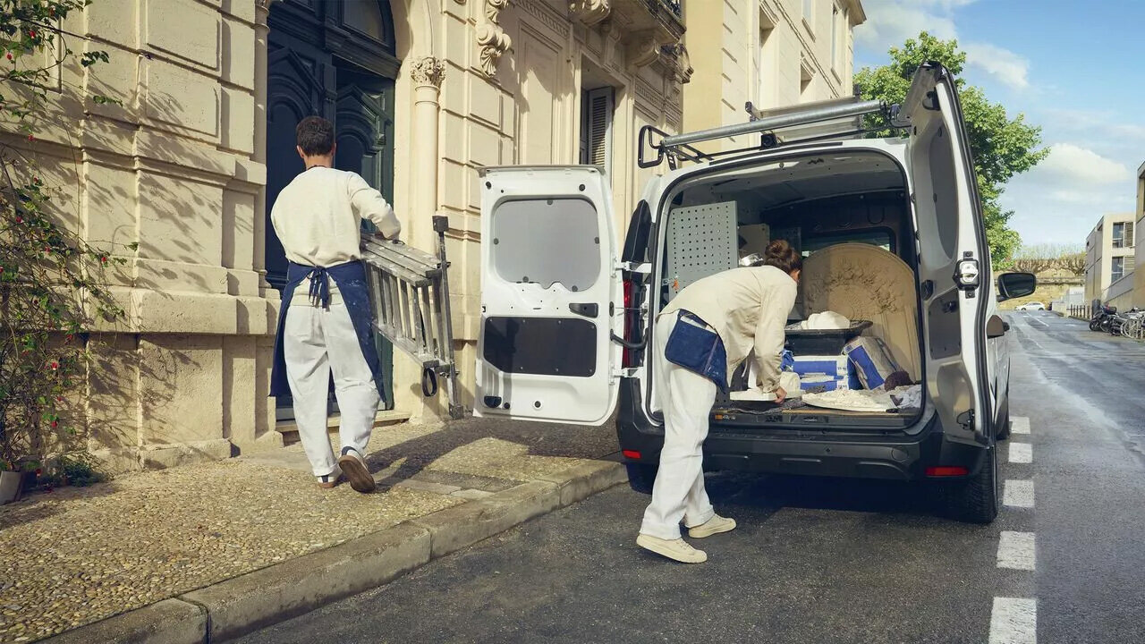 Handwerker beladen einen Kastenwagen vor einem Gebäude, idealer Transporter für Bauarbeiten und Renovierungen.